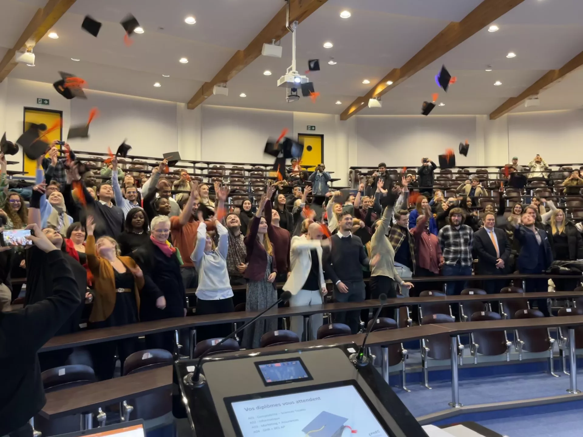 Etudiants qui jettent leur chapeau en l'air, dans un auditoire